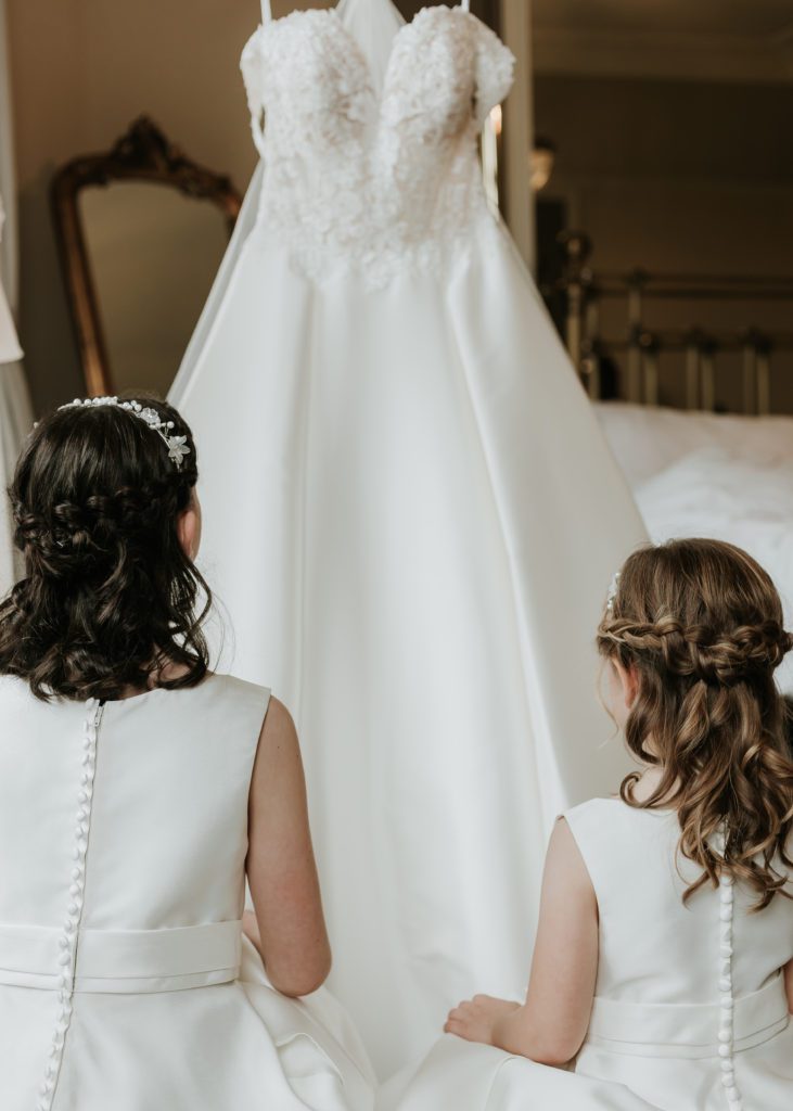 Flowergirls looking at brides dress