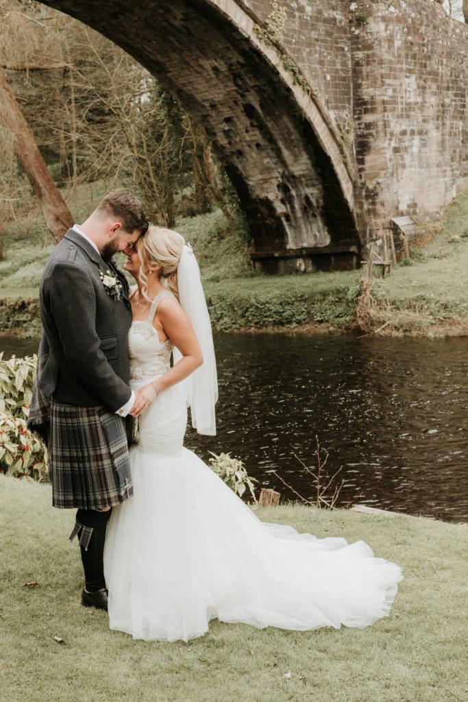 Bride and groom at brig o doon under the bride snuggling